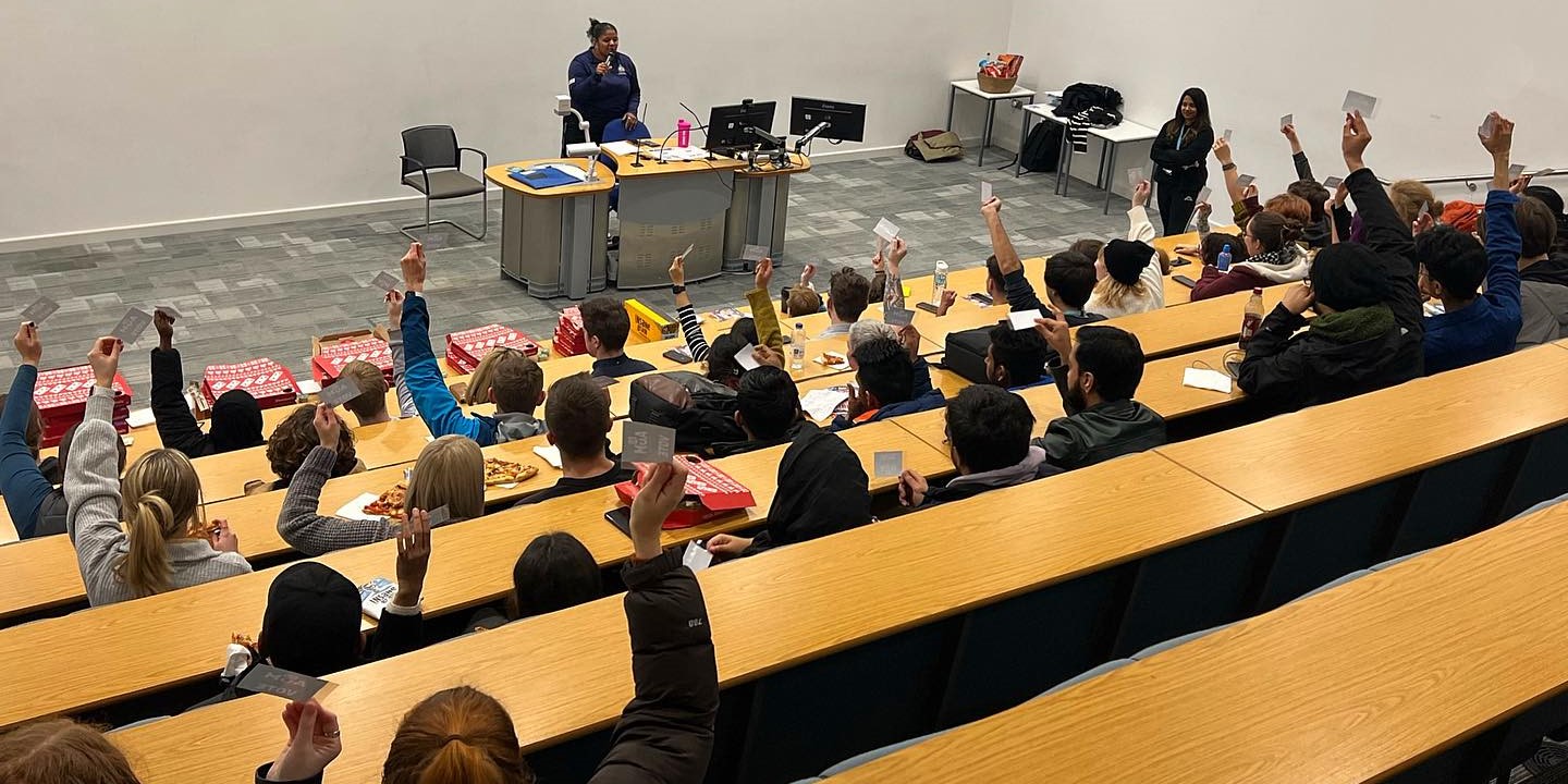Students attending Cmet SU AGM raising their hands in the air with their voting cards.